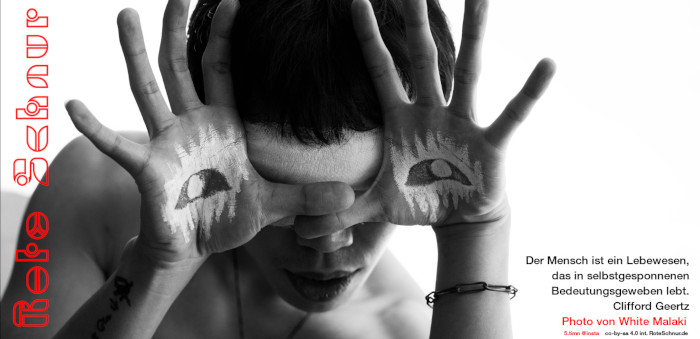 H&auml;nde mit gespreizten Fingern und aufgemalten Augen vor einem Gesicht mit verbundenen Augen